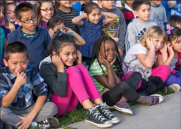 A group of smiling children sitting together outdoors.